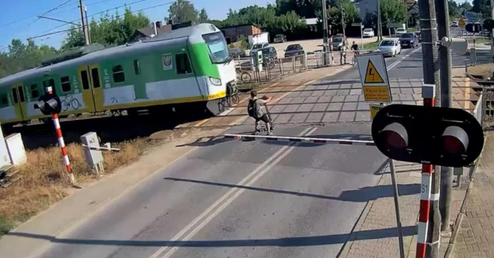 Patinete elétrico passa a centímetros de um trem em passagem de nível na Polônia, câmera flagra